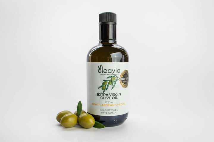 A 500 mL dark glass bottle of Oleavia Extra Virgin Olive Oil, featuring a white label with green olives and a gold seal, set against a plain white background.