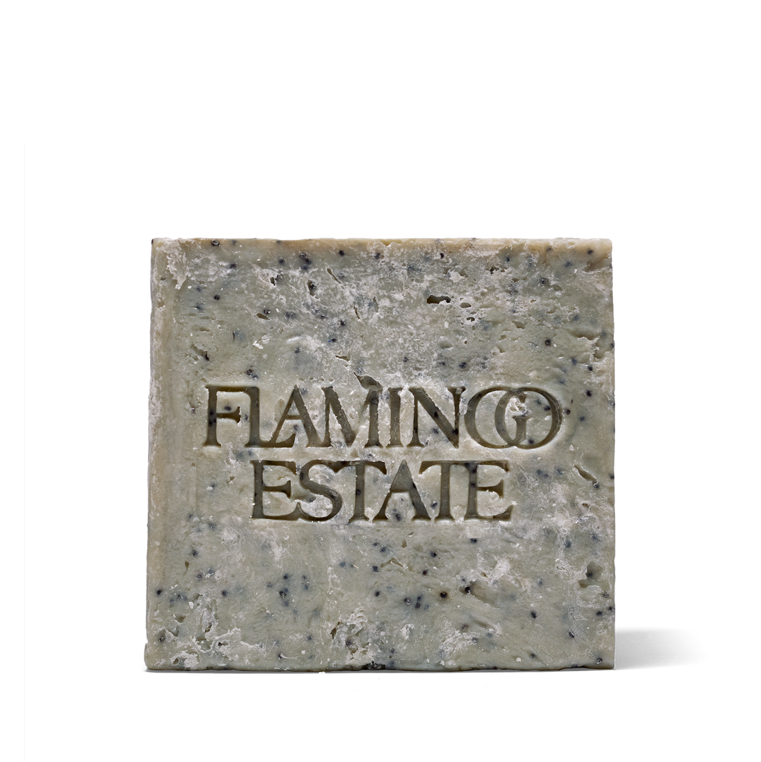 Grey-green Flamingo Estate soap brick speckled with black poppy seeds, front face embossed with the Flamingo Estate name