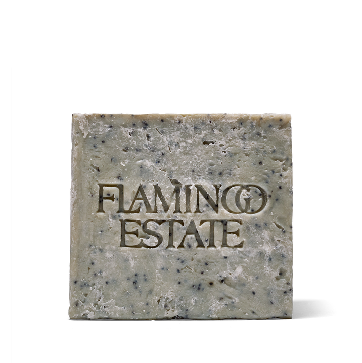 Grey-green Flamingo Estate soap brick speckled with black poppy seeds, front face embossed with the Flamingo Estate name