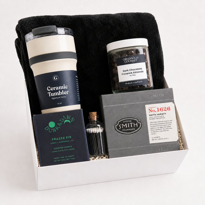Quiet Hour Gift Box with a black fleece throw blanket, a Signature Series ceramic travel tumbler, a Dusk &amp; Dawn Fraser Fir boxed candle, an apothecary match jar, a jar of dark chocolate covered almonds and a Smith Teamaker tea sampler in a white gift box