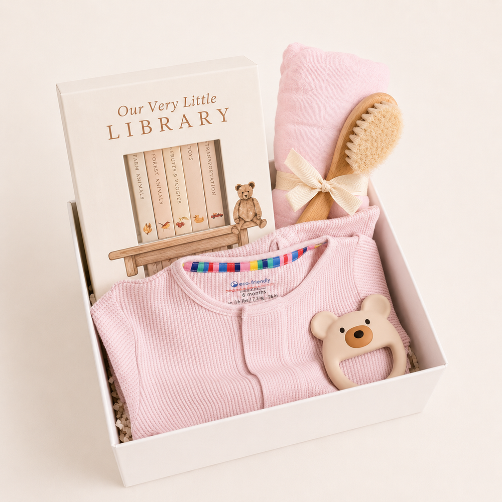 Sweet Beginnings Baby Gift Box in Lilac Snow: pink waffle footie, Our Very Little Library, pink swaddle, wooden brush and bear teether