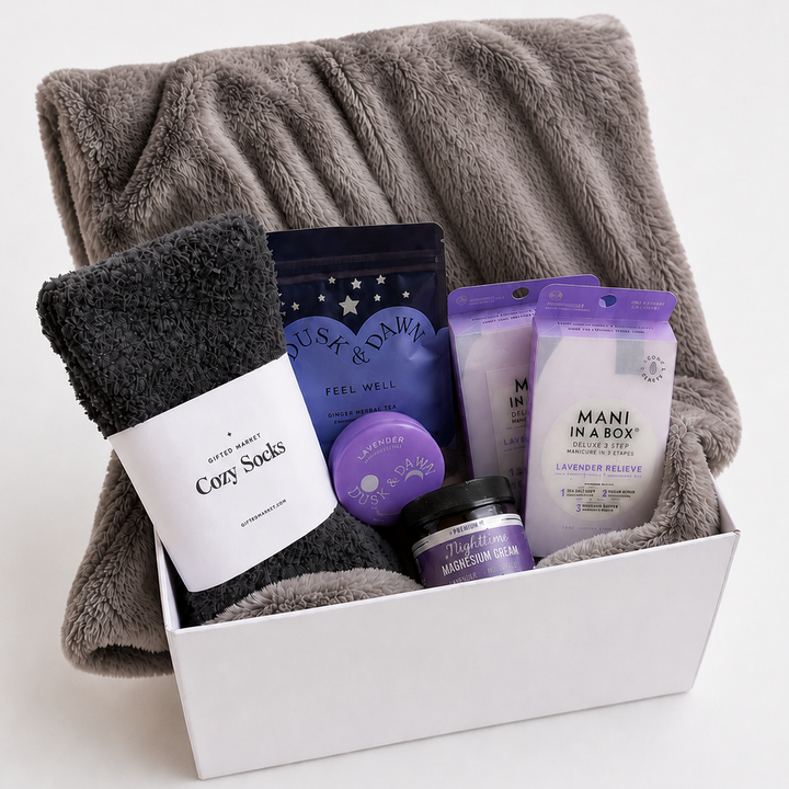 Gift set with gray blanket, socks, and skincare products in a box on a white background