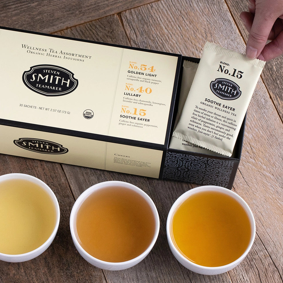 Wellness tea assortment gift box with three varieties and brewed tea in white cups