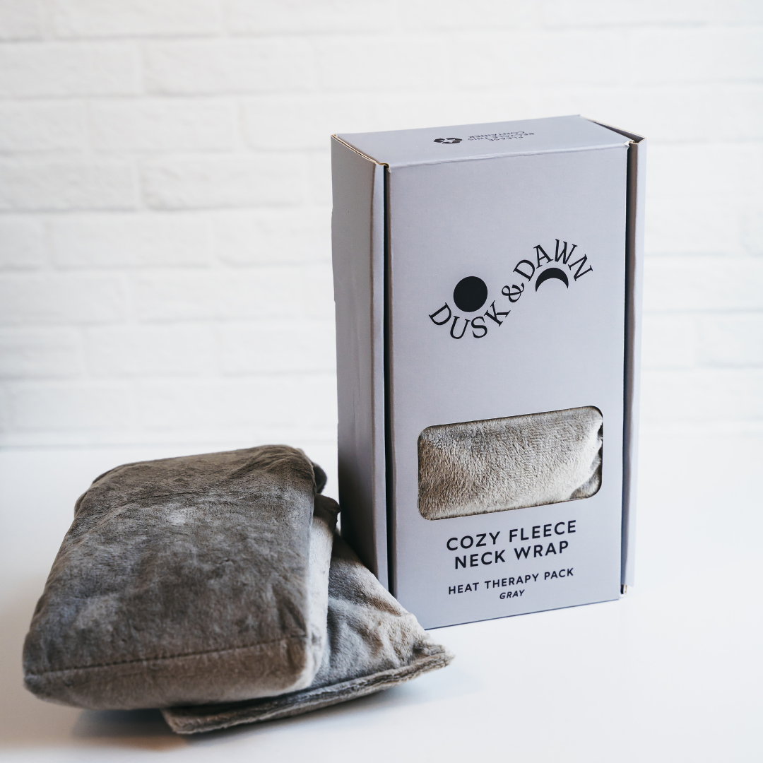 Gray Cozy Fleece Neck Wrap beside its Dusk &amp; Dawn gift box with a clear window