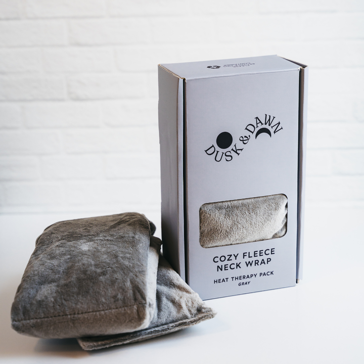 Gray Cozy Fleece Neck Wrap beside its Dusk &amp; Dawn gift box with a clear window
