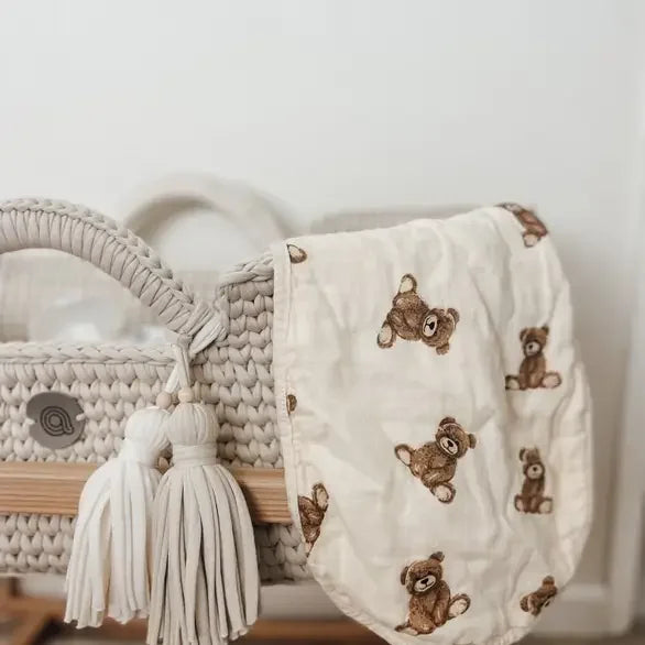 Soft muslin burp cloth with teddy bear print draped over a woven basket
