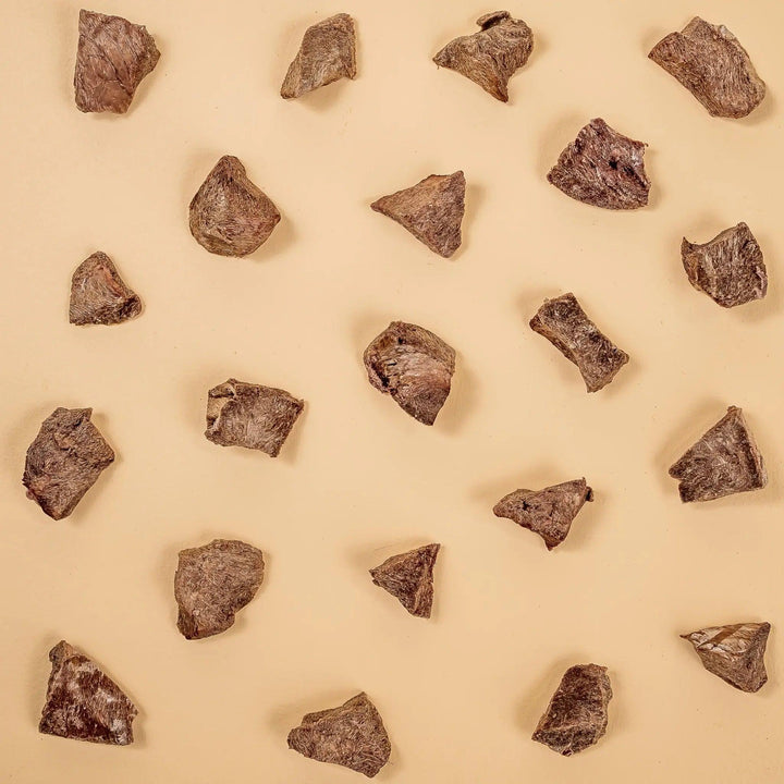 Bite-sized dried cat treats arranged on a neutral beige background