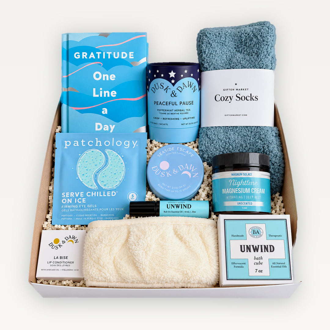 Breathe Deeply Gift Box, top view. Gratitude One Line a Day journal, Dusk & Dawn Peaceful Pause tea, Giften Cozy Socks, Patchology eye gels, Nighttime magnesium cream, Unwind rollerball and bath cube, La Bise lip conditioner, cream spa headband. Giften Market.