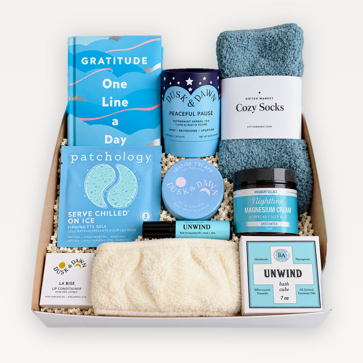 Breathe Deeply Gift Box, top view. Gratitude One Line a Day journal, Dusk &amp; Dawn Peaceful Pause tea, Giften Cozy Socks, Patchology eye gels, Nighttime magnesium cream, Unwind rollerball and bath cube, La Bise lip conditioner, cream spa headband. Giften Market.