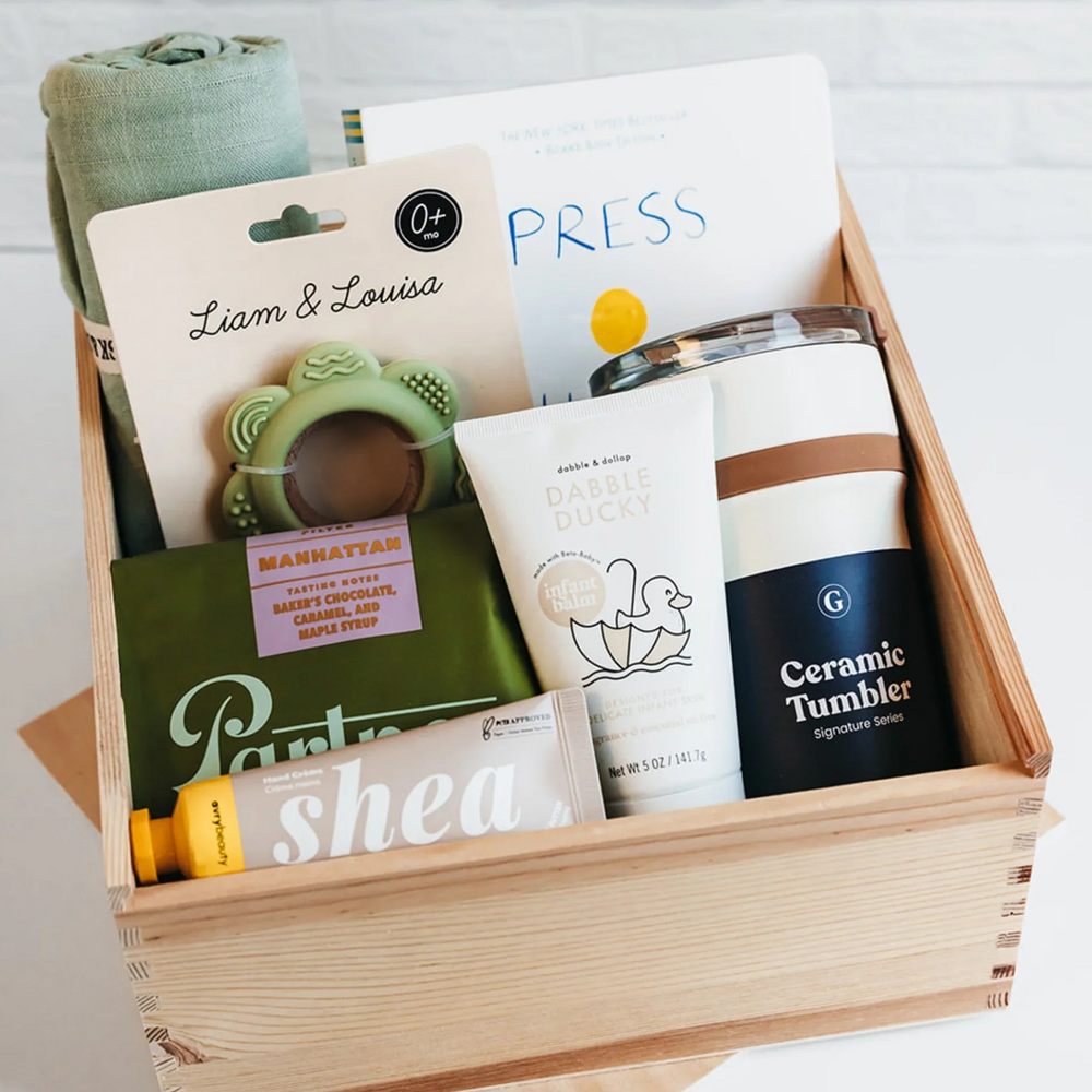 Wooden gift crate with sage baby blanket, teether, snacks, tumbler, and skincare items