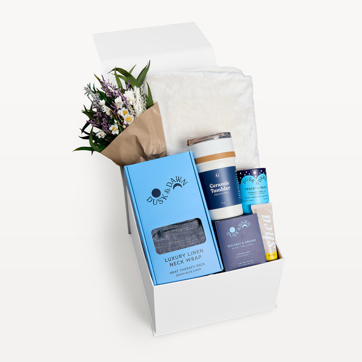 Comfort &amp; Care Cream + Blue Classic, white gift box, lid open. Cream faux-fur throw, dried bouquet, Luxury Linen Neck Wrap in the blue box, navy Ceramic Tumbler, Peaceful Pause tea, Sea Salt &amp; Orchid candle, Shea bar. Giften Market.