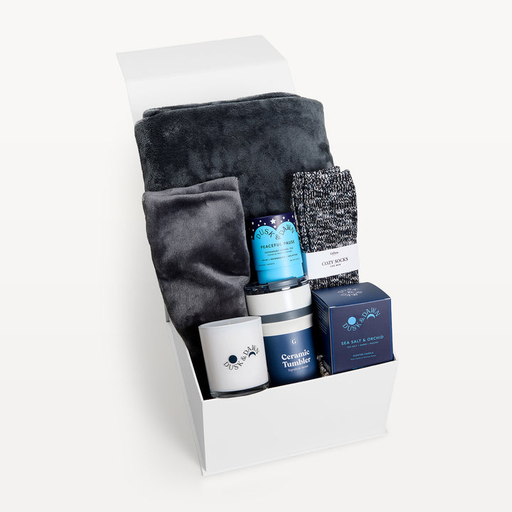 Comfort &amp; Care for Men, white gift box, lid open. Charcoal faux-fur throw, marled Cozy Socks, Peaceful Pause tea, cream candle, Ceramic Tumbler, Sea Salt &amp; Orchid candle box. Giften Market.