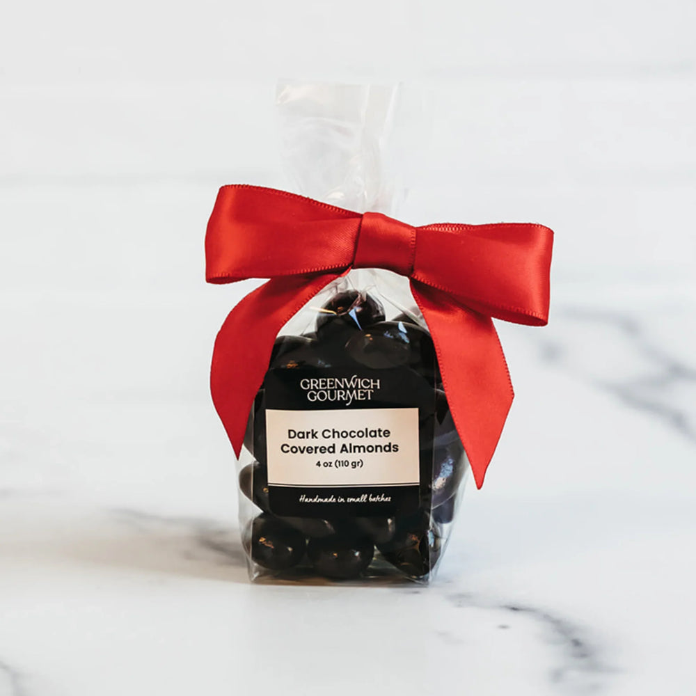 Packaged dark chocolate covered almonds with a red bow on a light background