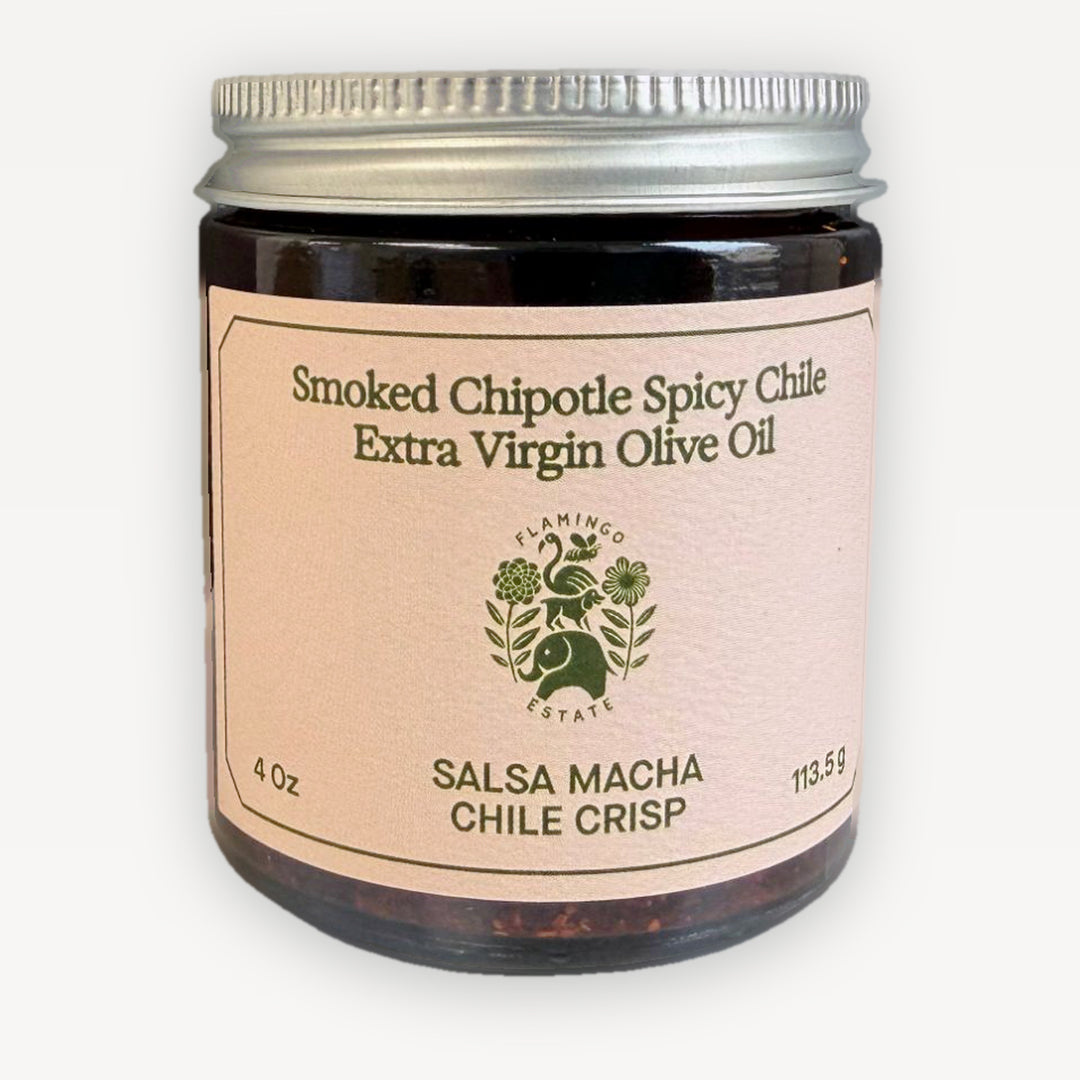 Flamingo Estate Salsa Macha Chile Crisp, a 4 oz amber glass jar with a silver screw lid and a blush label reading Smoked Chipotle Spicy Chile Extra Virgin Olive Oil, on a white background