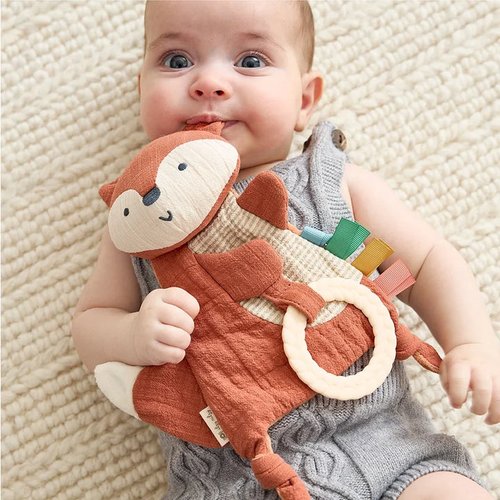 Baby holding soft fox sensory toy with textured teether and colorful fabric tags