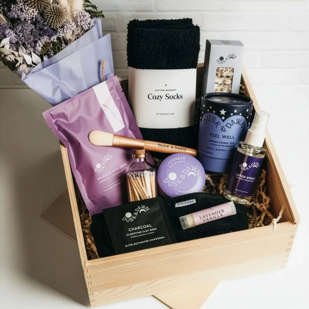 Wooden gift crate with cozy socks, tea, bath soak, dried flowers, and self-care items