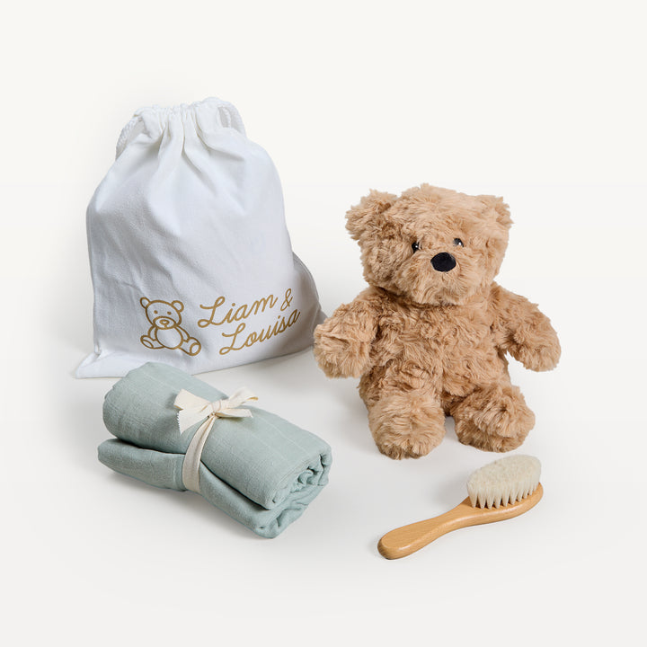 Liam &amp; Louisa Snuggle Set, Archie Bear in sage green, loose on the sweep: drawstring bag, tan bear, rolled sage swaddle, wooden brush. Giften Market.