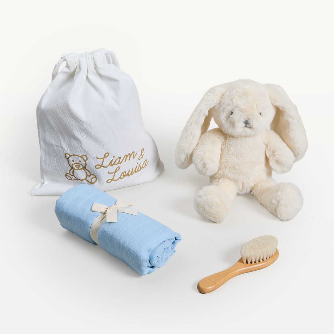 Liam &amp; Louisa Snuggle Set, Bea Bunny in blue, loose on the sweep: Liam &amp; Louisa drawstring bag, cream bunny, rolled blue muslin swaddle with bow, wooden brush. Giften Market.