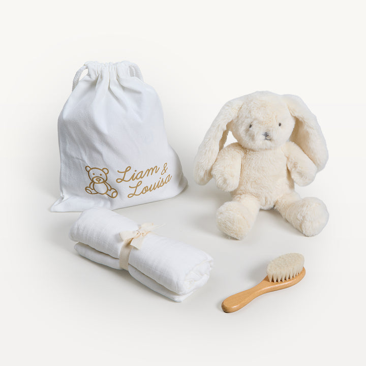 Liam &amp; Louisa Snuggle Set, Bea Bunny in ivory, loose on the sweep: drawstring bag, cream bunny, rolled ivory swaddle, wooden brush. Giften Market.