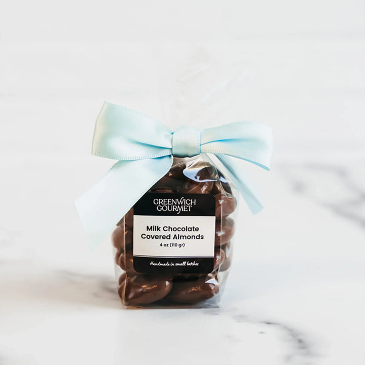 Packaged milk chocolate covered almonds with a blue bow on a light background