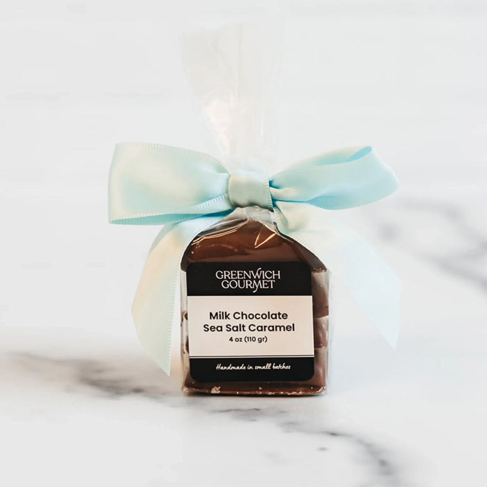 Greenwich Gourmet milk chocolate sea salt caramel package with a light blue ribbon on a marble surface.