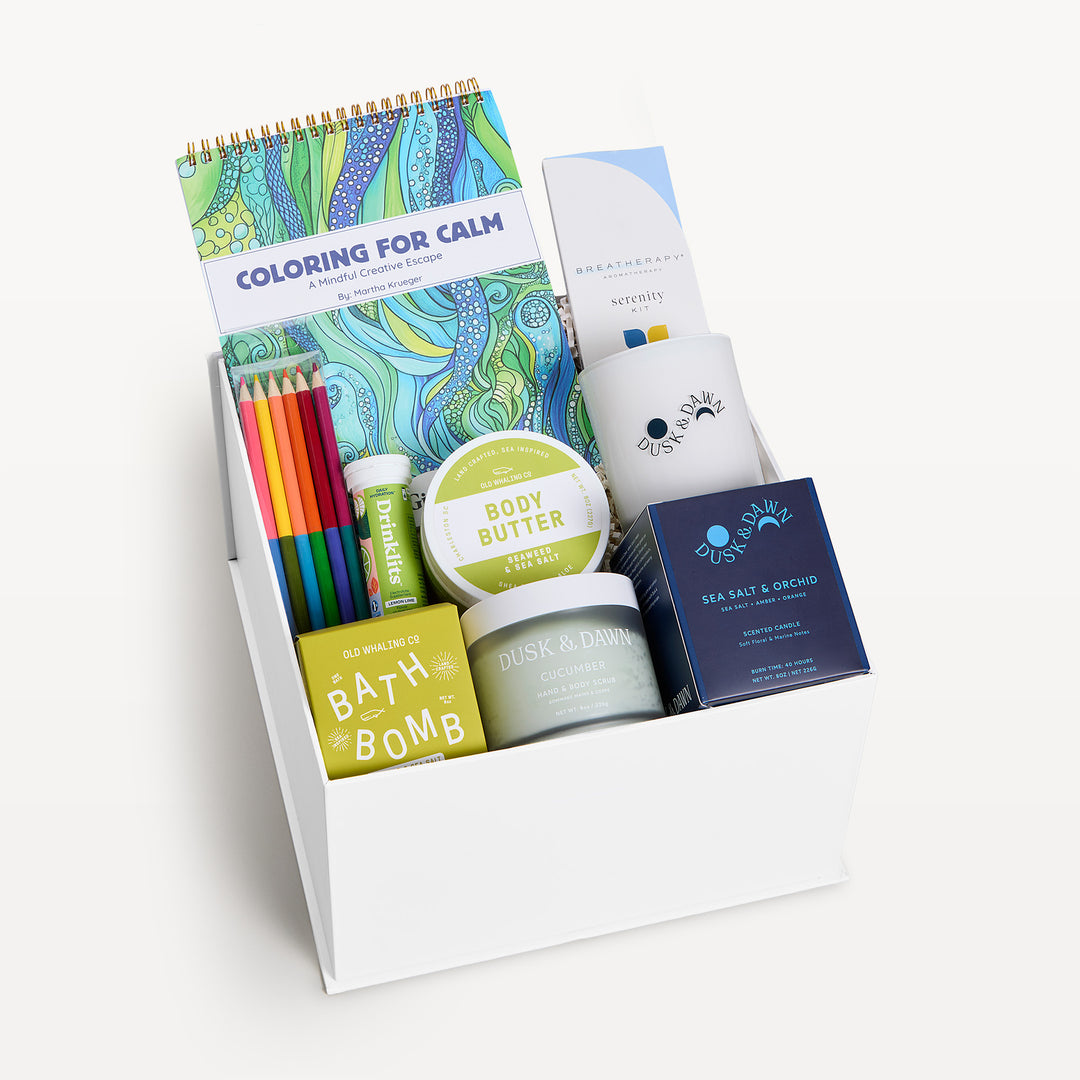 Mindfulness Deluxe, white gift box, lid off. Coloring for Calm book with colored pencils, Old Whaling bath bomb, Harvest body butter, cream candle, Sea Salt &amp; Orchid candle box, Breatherapy, Dusk &amp; Dawn tin. Giften Market.