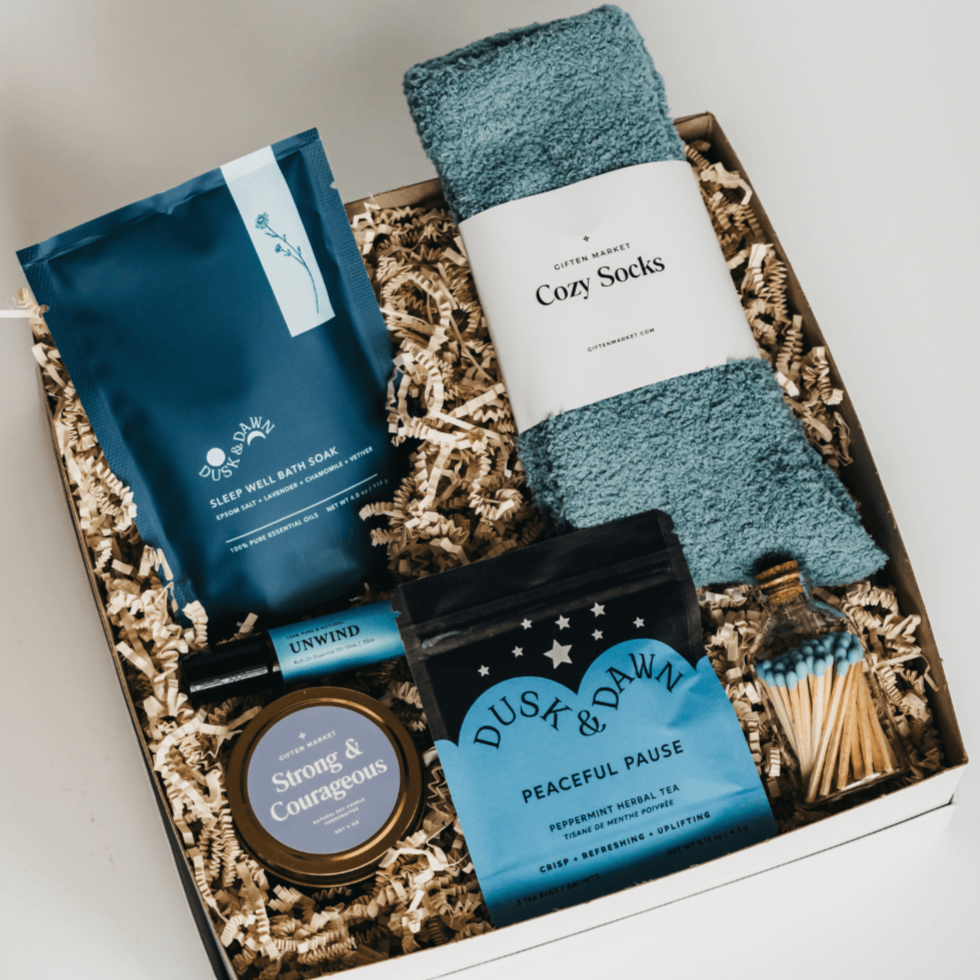 Peaceful Pause Gift Box open with teal cozy socks, Dusk & Dawn Peaceful Pause tea, bath soak, gold candle tin, matches and roller