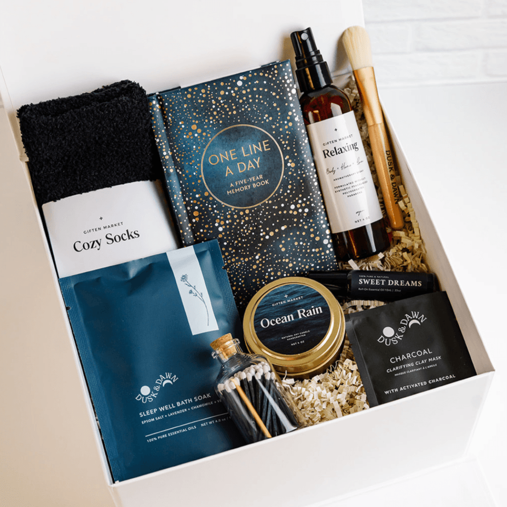 Peaceful Retreat Gift Box packed with journal, cozy socks, body spray, mask brush, Ocean Rain candle tin, matches and charcoal clay mask
