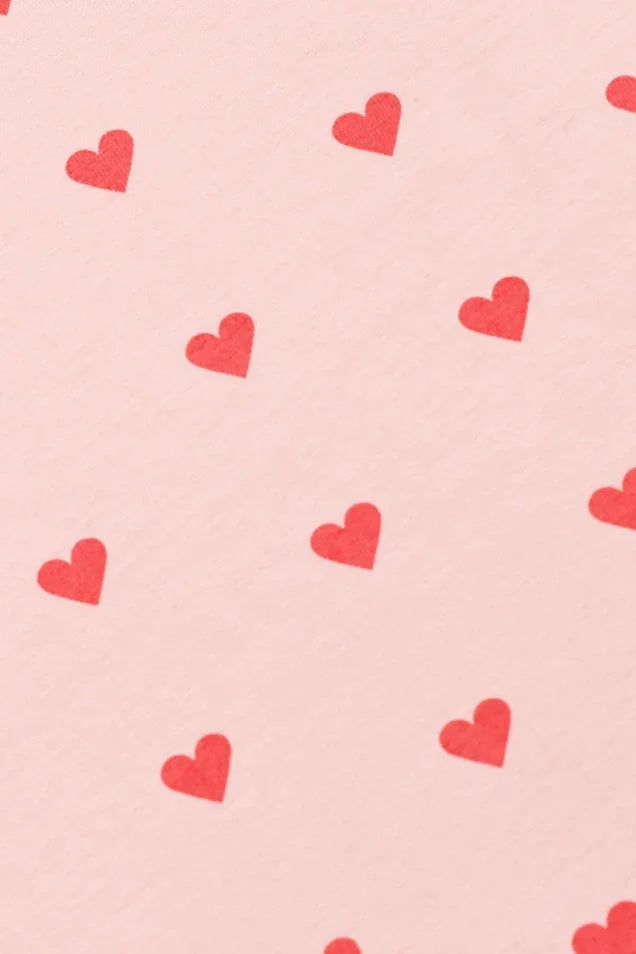 Soft pink organic cotton fabric with scattered red heart print, baby clothing detail
