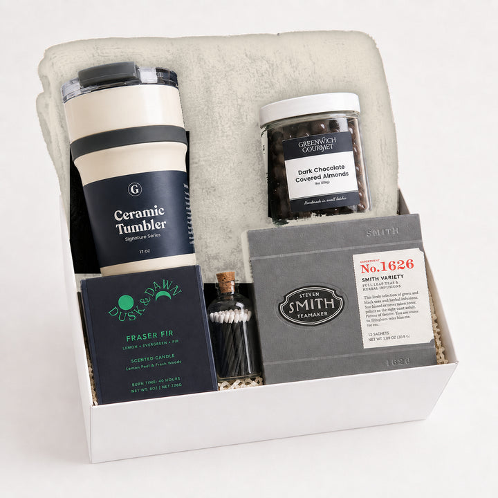 Quiet Hour Gift Box with a cream fleece throw blanket, a Signature Series ceramic travel tumbler, a Dusk &amp; Dawn Fraser Fir boxed candle, an apothecary match jar, a jar of dark chocolate covered almonds and a Smith Teamaker tea sampler in a white gift box