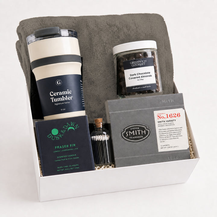 Quiet Hour Gift Box with a gray fleece throw blanket, a Signature Series ceramic travel tumbler, a Dusk &amp; Dawn Fraser Fir boxed candle, an apothecary match jar, a jar of dark chocolate covered almonds and a Smith Teamaker tea sampler in a white gift box