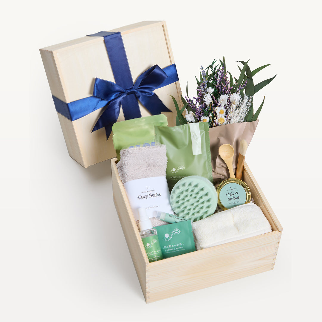 Soothing Sanctuary Classic crate open in front, bow-tied lid propped behind. Wildflower bouquet, Cozy Socks, Oak & Amber candle tin, green scalp massager, Refresh Mint clay mask, spray. Giften Market.