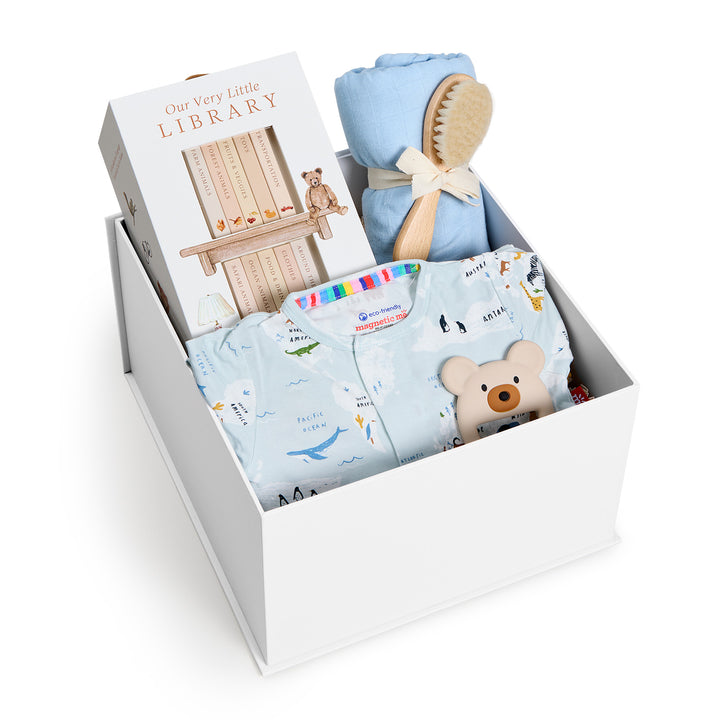 Sweet Beginnings Sea the World, white gift box, lid off. Pale blue world-map print zip onesie, Our Very Little Library, blue swaddle, wooden brush, bear teether. Giften Market.