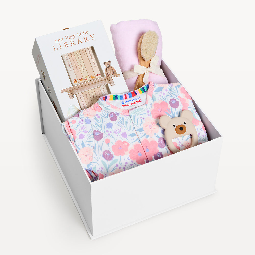 Sweet Beginnings Whistledon, white gift box, lid off. Pink and lilac floral zip onesie, Our Very Little Library, pink swaddle, wooden brush, bear teether. Giften Market.
