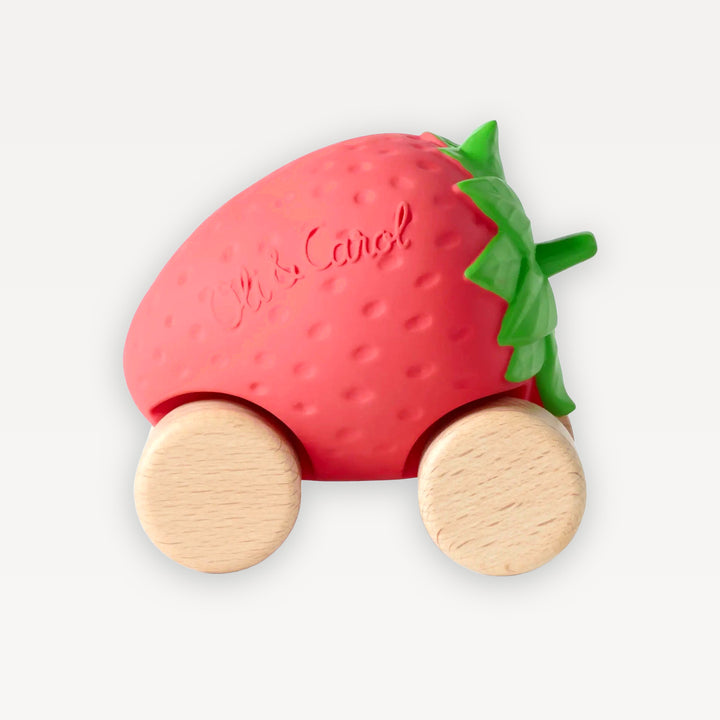 Sweetie the Strawberry Baby Car by Oli &amp; Carol: red dimpled natural rubber strawberry with green leaves on four beech wood wheels, on a warm white background