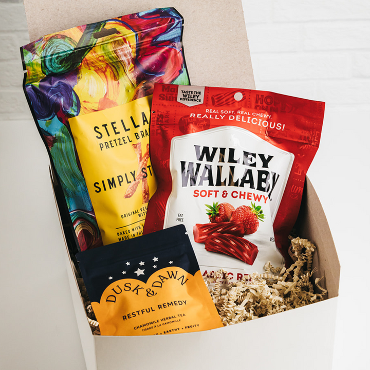 Assorted snacks including Stellar Pretzel Brand, Wiley Wallaby, and Dusk & Dawn Tea in a box.