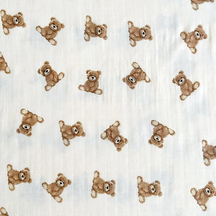 White muslin baby blanket with repeating brown teddy bear pattern