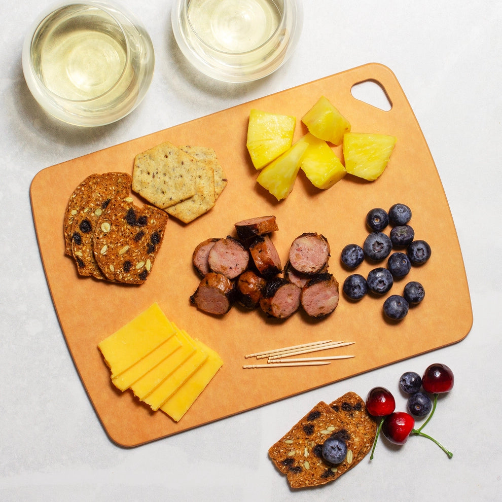 Charcuterie cutting board with crackers, cheese, sausage, pineapple, blueberries, and cherries