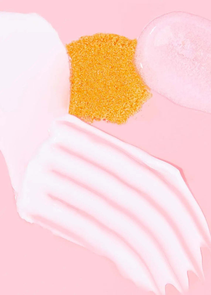Rose-infused pedi kit textures including scrub, cream, and gel on a pink background