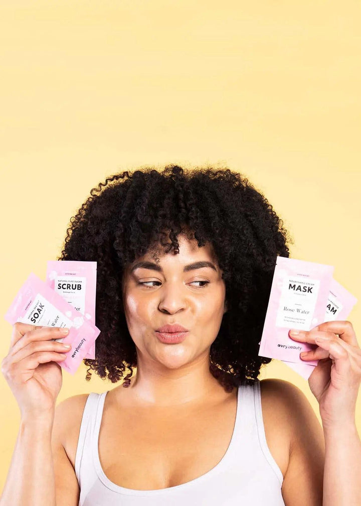 Woman holding rose water pedicure kit sachets against yellow background